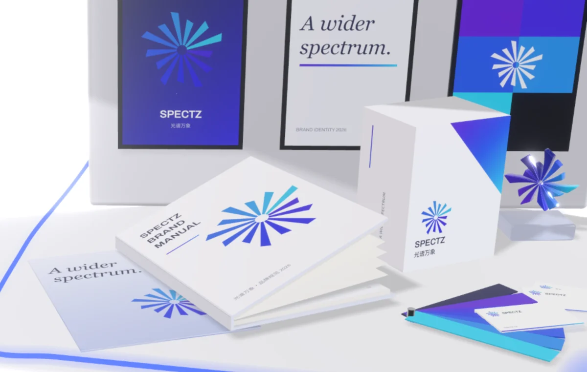 浮在空中翻开的 SPECTZ 品牌手册、印着星芒标志的产品盒、一把色卡扇与名片,后方是品牌海报墙